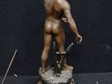 a bronze statue of a man with a gun and a knife
