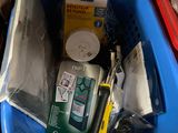 a blue basket filled with electronics and other items on the floor