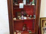 une armoire avec une porte vitrée et une chaise rouge devant
