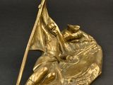 brass statue of a man holding a flag on top of a boat