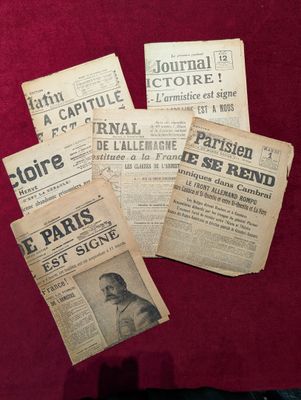 plusieurs vieux journaux français posés sur une table rouge
