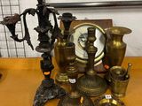 de nombreux objets en laiton posés sur une table où se trouve une horloge