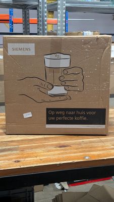 une boîte en carton posée sur une table, avec une main tenant une tasse de café