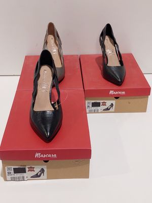 une paire de chaussures à talons hauts noires et marron posées sur une boîte rouge