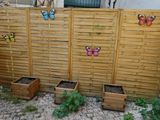 a wooden fence with butterfly decorations on it next to some planters