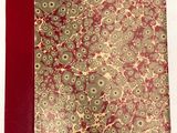 un gros plan d'un livre à la couverture rouge ornée de fleurs dorées