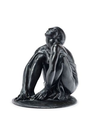 a black statue of a man sitting on a white surface