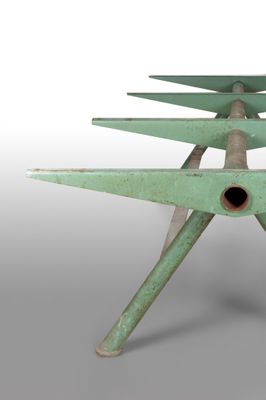 a green metal table with four legs and a hole in the middle of it