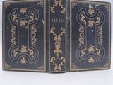 an old black book with gold trim sitting on top of a white surface