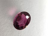 a close up of a purple gemstone on a white surface