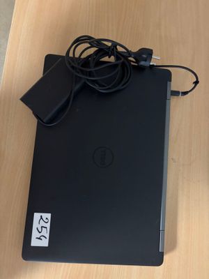 dell laptop with power cord and charger sitting on a wooden table