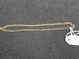a gold chain with a small white tag on it