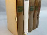 three books are stacked on top of each other on a white surface
