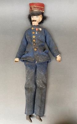 une petite poupée qui porte un uniforme et un chapeau