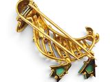 an image of a gold broochle with green stones on it