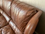 a brown leather couch sitting in a corner of a room