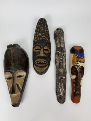 trois masques africains sont exposés sur un fond blanc
