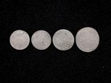 four silver coins are arranged in a row on a black surface
