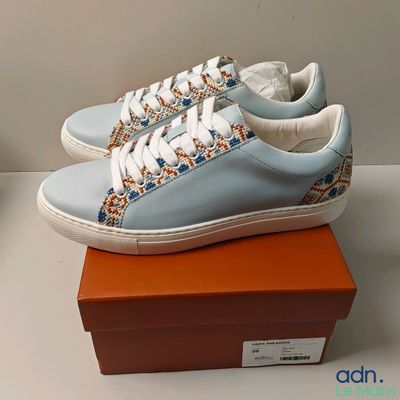 Quelqu'un porte une paire de baskets bleues avec des lacets blancs.