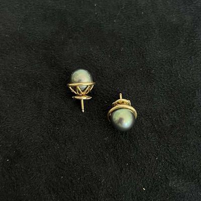 une paire de boucles d'oreilles en perles et en or posées sur un fond noir
