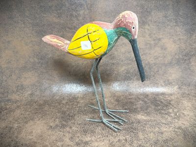 a bird that is standing on the ground with a stick in it ' s beak