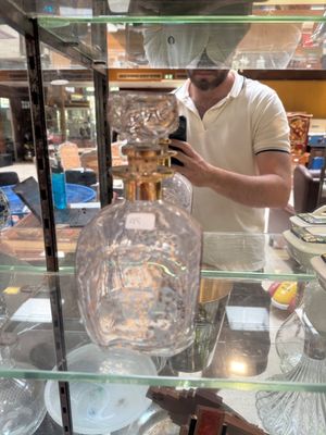 a man standing behind a glass case holding a cell phone