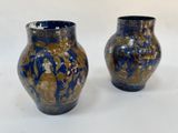 une paire de vases bleus et dorés posés sur une surface blanche