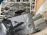 a pile of old photos on a desk next to a laptop