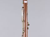 a wooden bassoon with brass fittings on a clear base