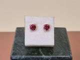 a pair of red earrings sitting on top of a marble block