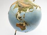 a small blue globe on a stand with a wooden stick sticking out of it