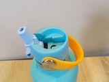 a blue water bottle with a yellow handle on a wooden table