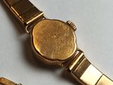 a gold watch that is laying on a white surface