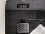a black projector with a remote on top of it