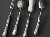 three spoons, a fork, and a knife on a black surface