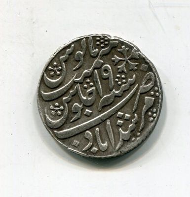 une vieille pièce de monnaie portant une inscription en arabe, posée sur une surface blanche