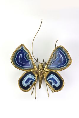 broche en forme de papillon bleu et or sur fond blanc