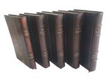 six vieux livres alignés sur une surface blanche