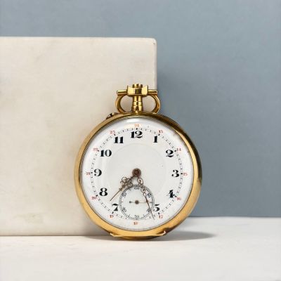 une montre de poche en or posée sur un bloc de marbre
