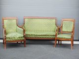 deux fauteuils rembourrés verts et un canapé devant une porte de garage