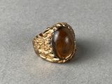 un gros plan d'une bague en or sertie d'une pierre brune