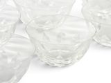 several clear glass bowls and cups are lined up on a white surface