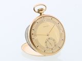une montre de poche en or posée sur une table en verre