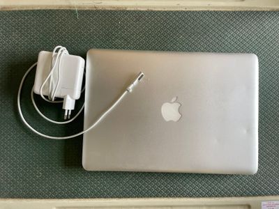 un ordinateur portable Apple et un chargeur posés sur la table