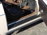 a white car with the door open and a black seat in the back