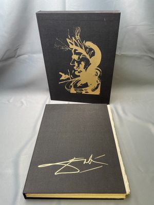 the book is sitting on a white sheet with a gold drawing on it