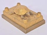 une statue en or représentant une tortue posée sur un socle