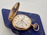 une image représentant une montre de poche posée sur une feuille de papier bleue