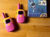 deux talkies-walkies roses et jaunes posés sur une table en bois
