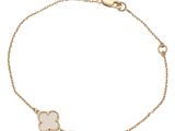 a gold bracelet with a white flower on a chain